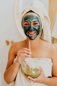 I woman in a natural holistic facemask holding a natural therapy juice drink