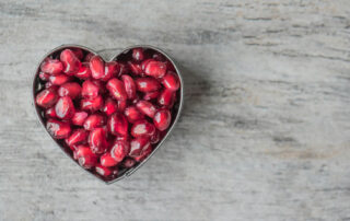 A heart shaped bowl of pomegranate seeds for holistic POTS support