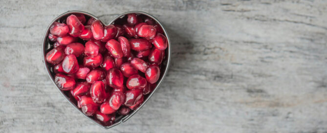 A heart shaped bowl of pomegranate seeds for holistic POTS support