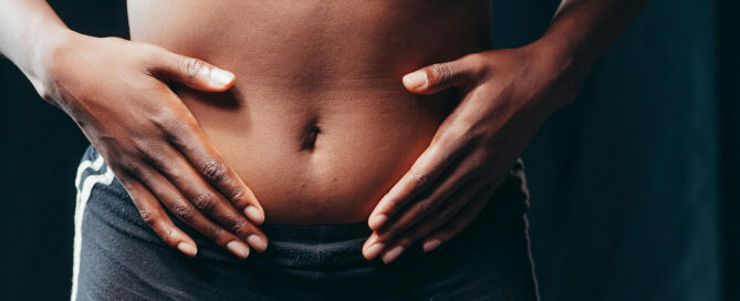 A woman holding her gut needing holistic parasite cleansing